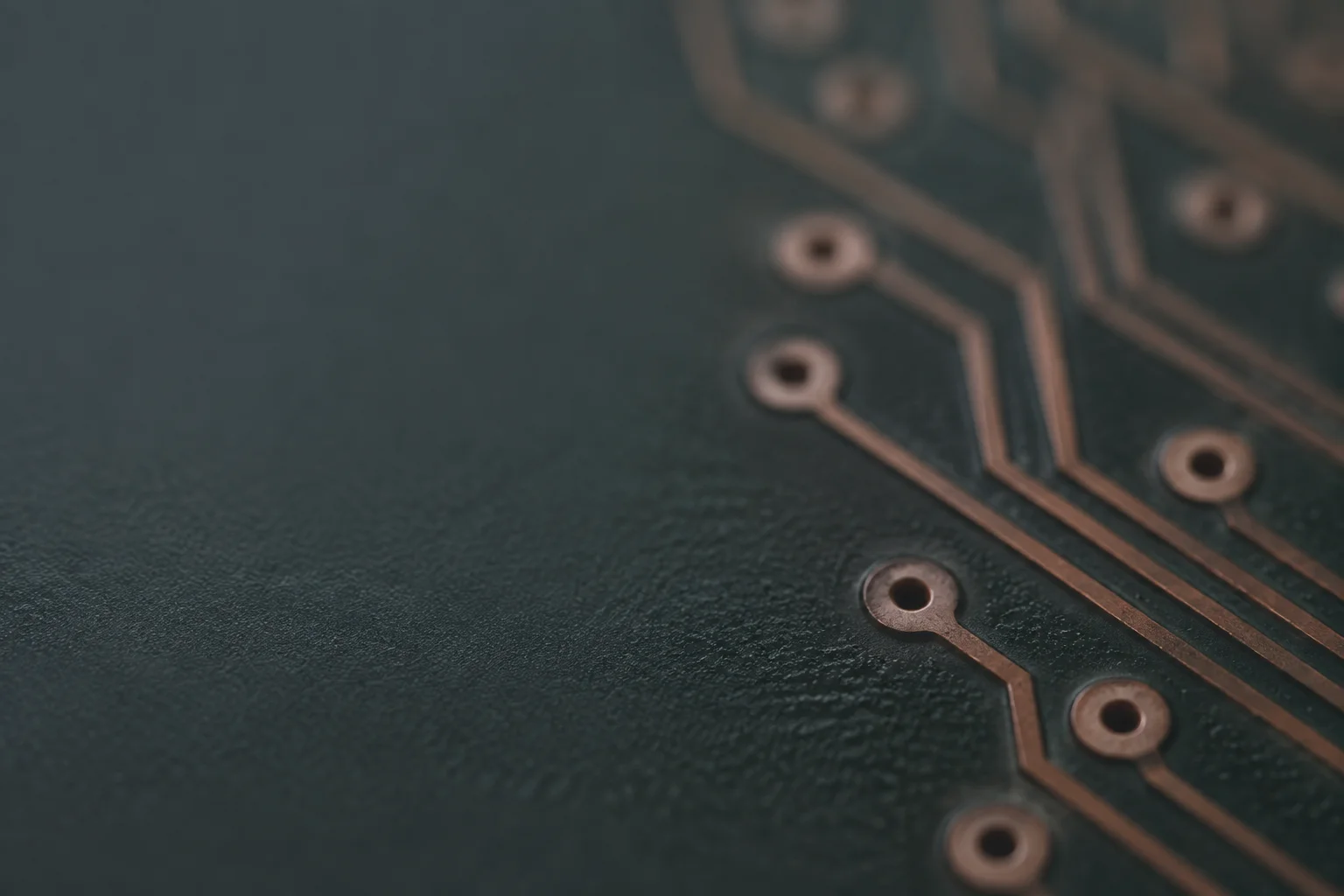 Softly lit out-of-focus circuit board surface with faint copper traces and via pads